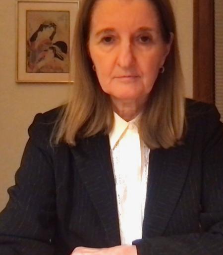 Cathy Caruth sits at her desk, wearing a dark blazer and white shirt. 